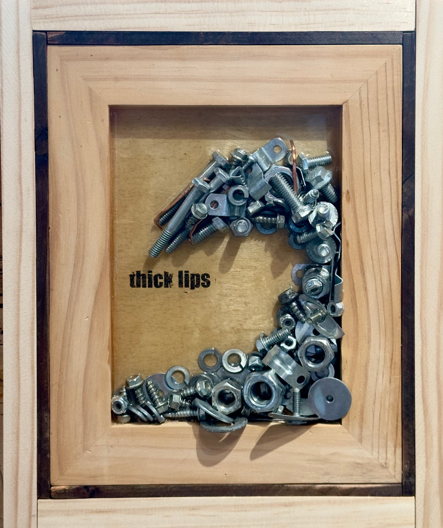 Wave made of nuts and bolts on wood panel toner